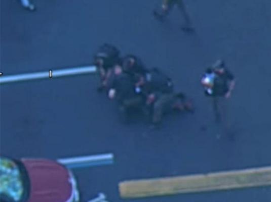 Momentul în care suspectul este imobilizat de polițiști, un agent ține un bebelus in brațe