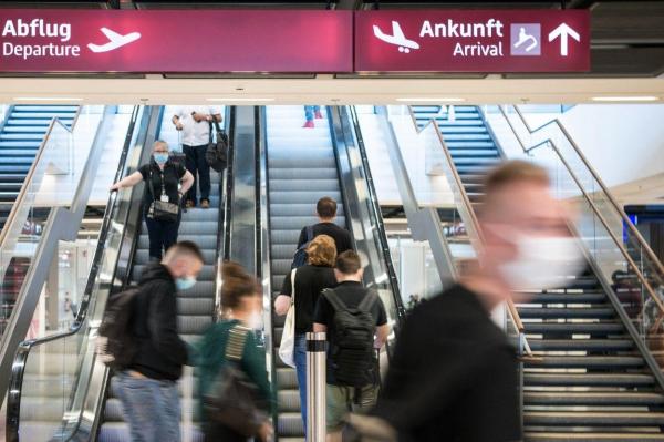 Pasageri cu măști de față și bagaje, într-un aeroport din Germania