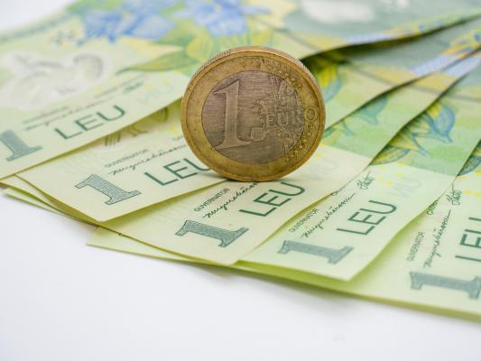 O monedă de 1 euro, aşezată pe bancnote de 1 RON