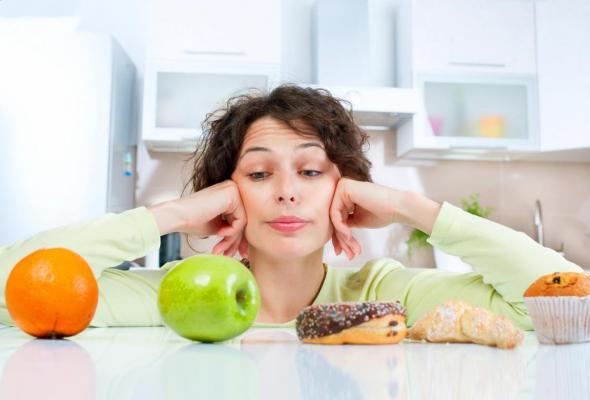 Tânără care alege între fructe și dulciuri