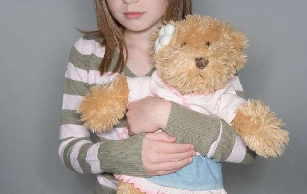 Copil cu un urs de pluş în braţe