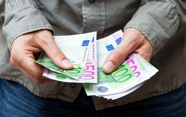 Un bărbat numără mai mulţi bani cash, în bancnote de 100 şi 500 de euro