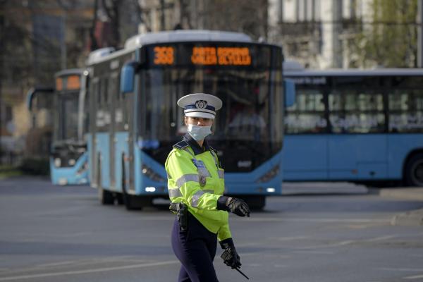 O poliţistă cu mască de protecţie dirijează traficul în Bucureşti