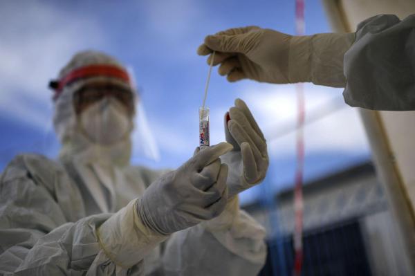 Un pacient pune proba de test Covid in eprubeta oferita de un asistent medical