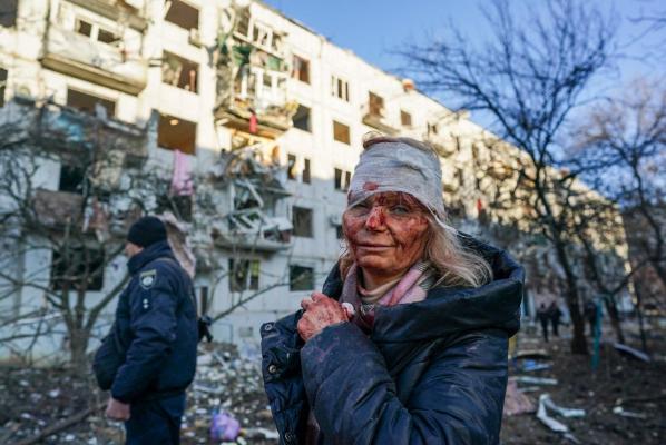 O femeie cu faţa plină de sânge stă în faţa unui bloc distrus de Rusia în urma unui bombardament, în Ucraina