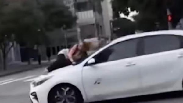 Momentul în care o femeie se agaţă de capota maşinii în viteză pentru a-şi salva câinele
