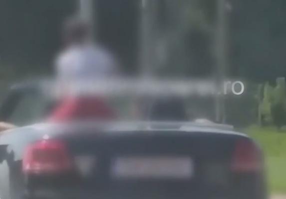 Copil plimbat minute în şir pe portbagajul unei maşini decapotabile, pe o stradă din Timiş (Video)
