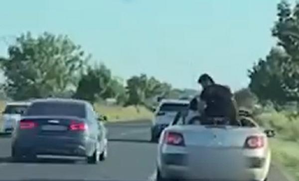 Un bărbat a fost filmat în timp ce se ridică în picioare pe bancheta unei decapotabile, pe E85. O fetiţă îi imită gestul