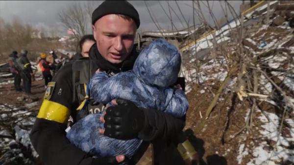 Un soldat ucrainean fuge cu un bebeluș ce-i plânge în brațe, ca să-l scape din bombardamentele de la Irpin