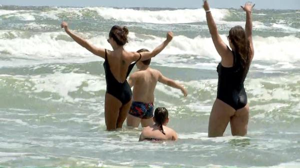 Turişti filmaţi cum dansează în valuri şi sfideză steagul roşu arborat pe litoral. Unii au intrat în mare şi cu copiii