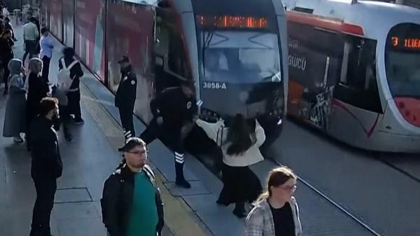 Momentul în care o femeie este trasă de pe şine din calea unui tramvai, în ultima secundă. Purta căşti