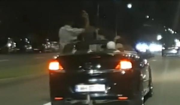 Momentul în care un şofer teribilist ia mâinile de pe volan şi se ridică in picioare, din decapotabilă