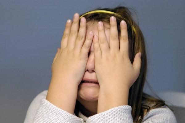 O fetiţa plânge, cu mâinile la ochi