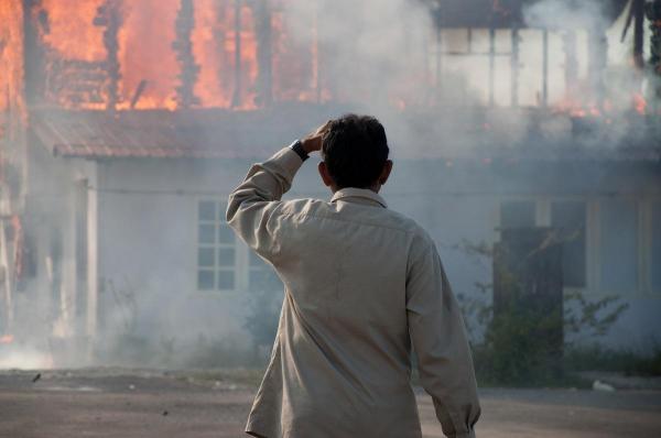 Bărbat care se uită la o casă în flăcări