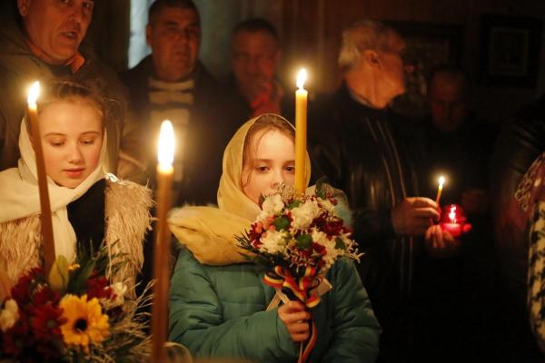 Fetiţă cu flori, ţinând o lumânare aprinsă în Biserică