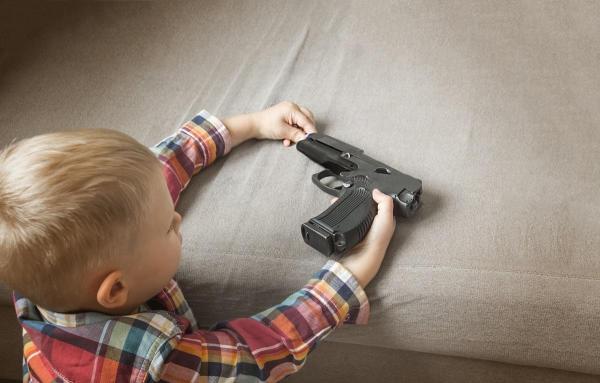 Băiat ţinând în mână un pistol