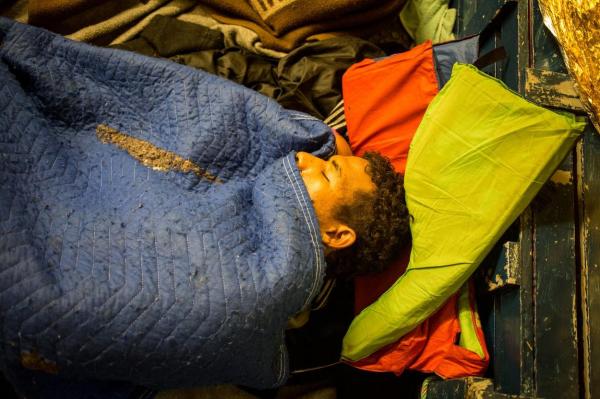 Un migrant doarme pe jos, într-un adăpost improvizat