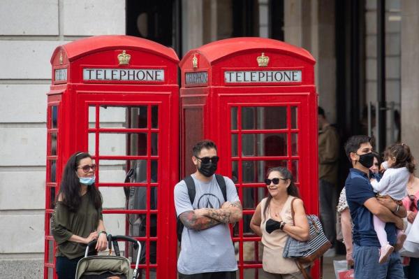 Persoane cu mască și fără mască așteaptă la semafor, în Londra