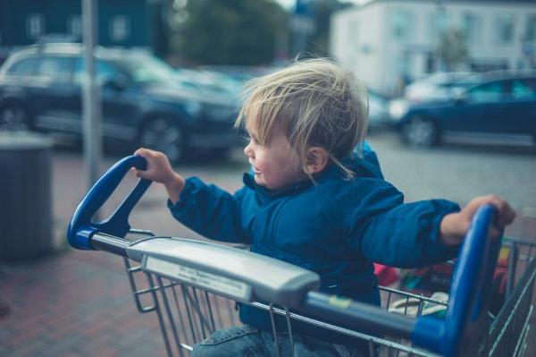 Copil în căruciorul de alimente al supermarket-ului