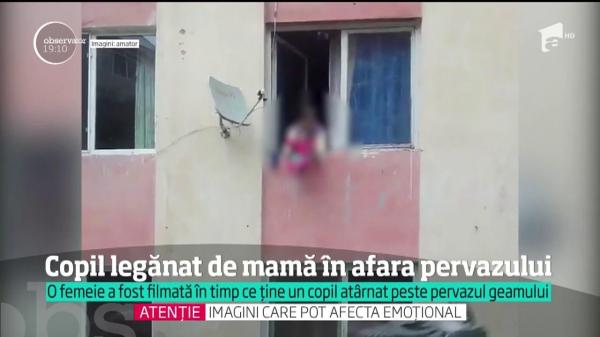 Scene ŞOCANTE la Zalău! O mamă, filmată în timp ce îşi ŢINE COPILUL ATÂRNAT în afara pervazului de la geam!