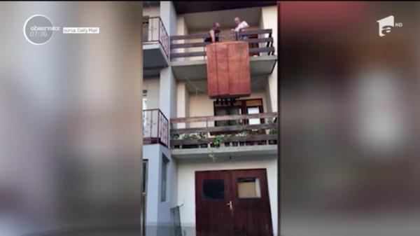 Imaginile cu doi bărbaţi care încearcă să coboare un şifonier de la etajul doi al unei clădiri fac furori pe Internet