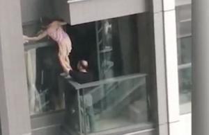 Imagini care-ți dau amețeală: o tânără s-a urcat pe balustrada balconului, la etajul 7, ca să spele un geam. S-a gândit mult ca să facă asta?