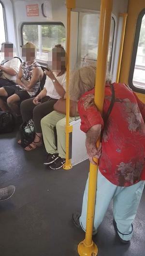 O bătrână stă în picioare, în tren, lângă trei tineri cu căştile în urechi, aşezaţi pe scaune (Foto)