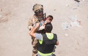 Lecţie de umanitate: Soldaţii străini ţin în braţe copiii aruncaţi peste sârma ghimpată, în timpul evacuărilor de pe aeroportul din Kabul - GALERIE FOTO