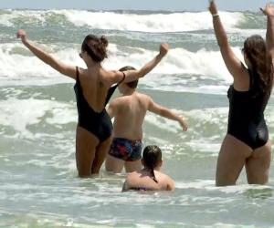 Turişti filmaţi cum dansează în valuri şi sfideză steagul roşu arborat pe litoral. Unii au intrat în mare şi cu copiii